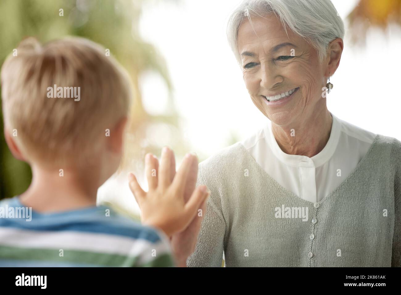 Covid, grandmother and child touching window for safety, social distancing and risk in covid 19 pandemic. Family, love and boy connect hand with Stock Photo