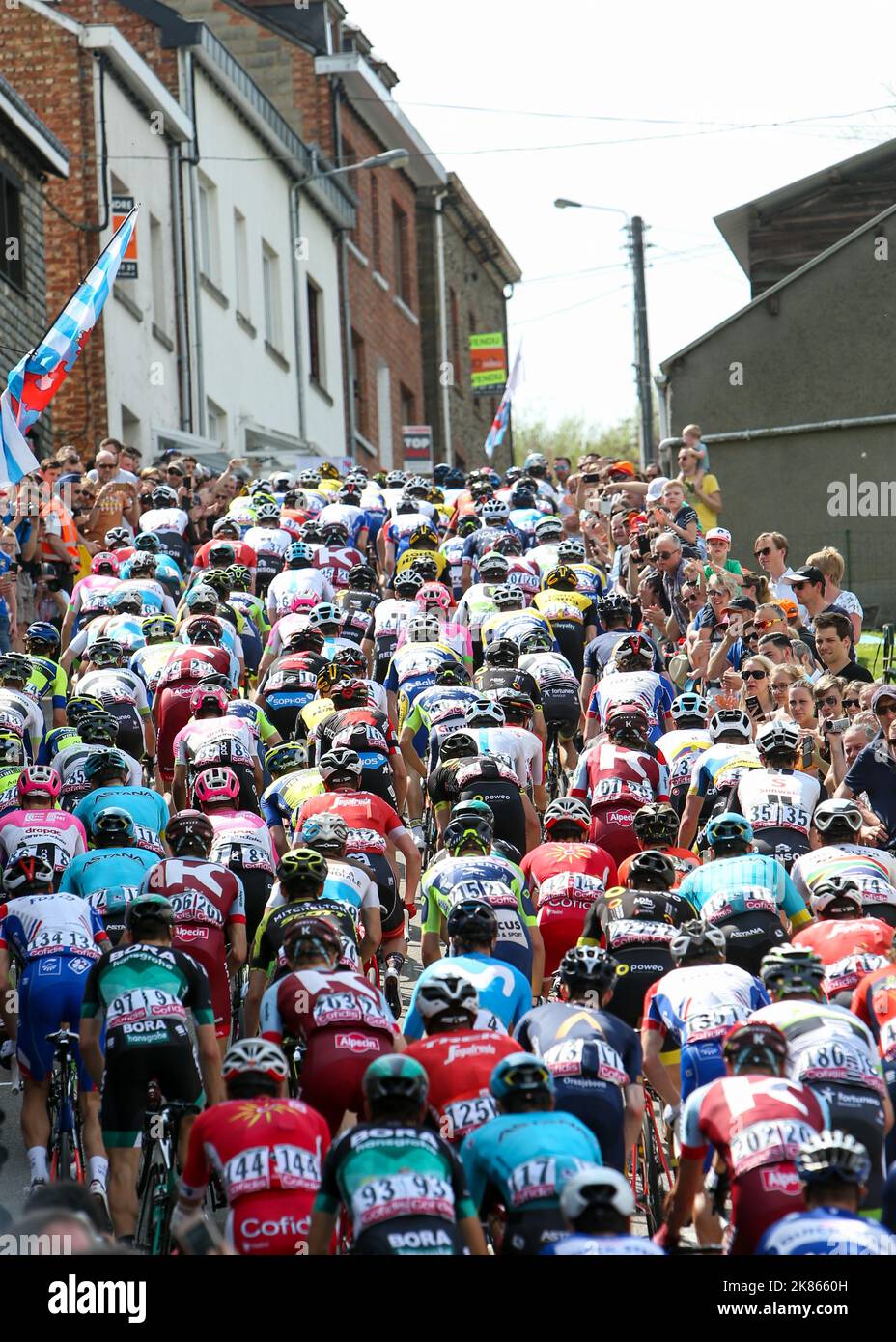 The Peloton climb through the lined streets in Houffalize on the climb of Cote de Saint Roch Stock Photo