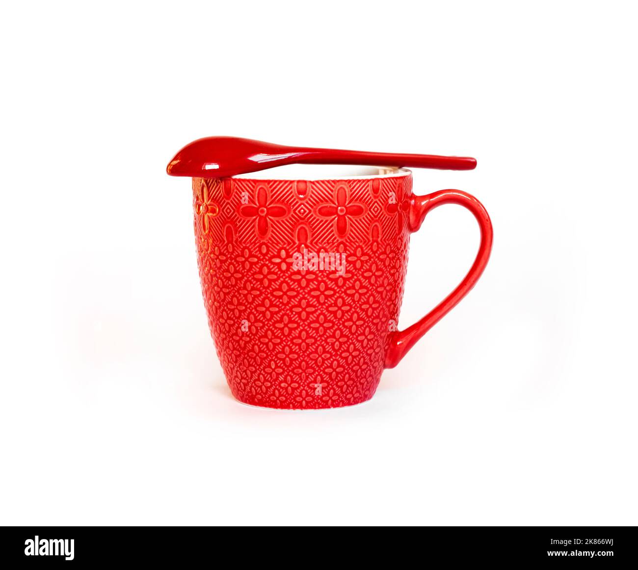 Red ceramic mug with red ceramic spoon lying over it isolated on white background Stock Photo