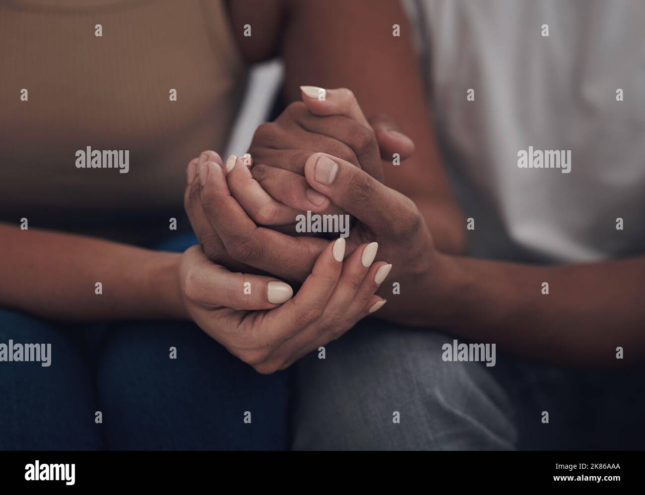 Lets use the strength of our love to overcome this. an unrecognizable couple sitting inside together and holding hands. Stock Photo