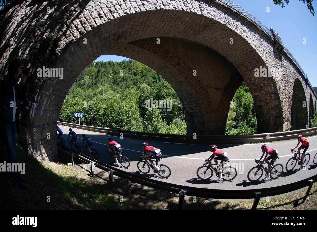 The chasing peloton including Alejandro Valverde and the Ineos Team with Geraint Thomas and Egan Bernal  ride under an archway bridge during the Tour de France 2019 Stage 5 - Saint-Die-Des-Vosges to Colmar Stock Photo