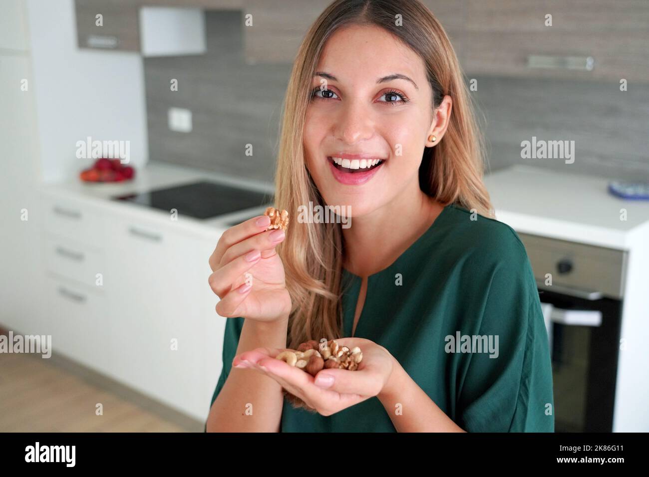Beautiful healthy woman eating mix of nuts seeds dried fruit indoor
