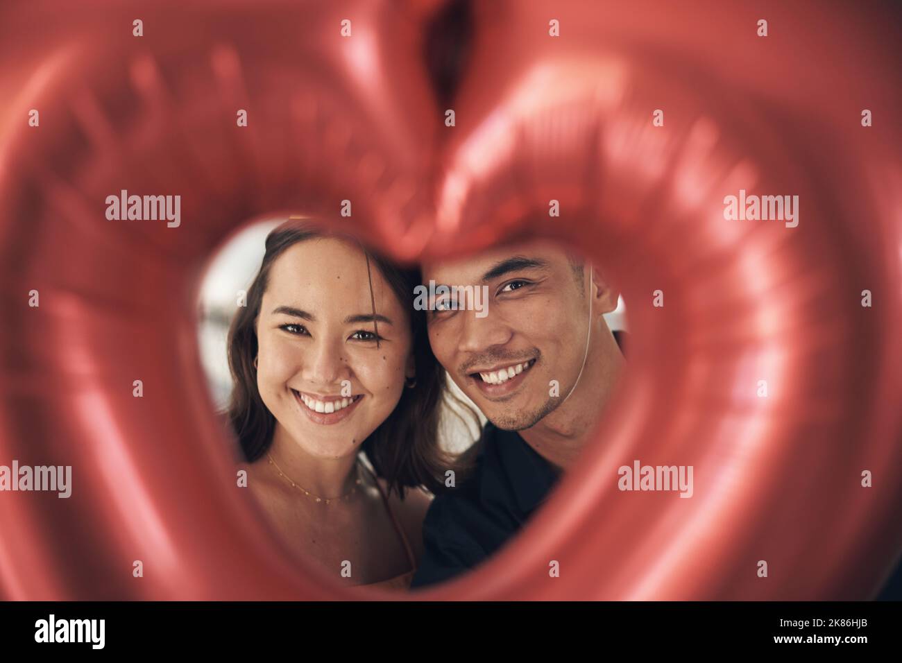 The perfect picture of love. a young couple posing through a heart ...