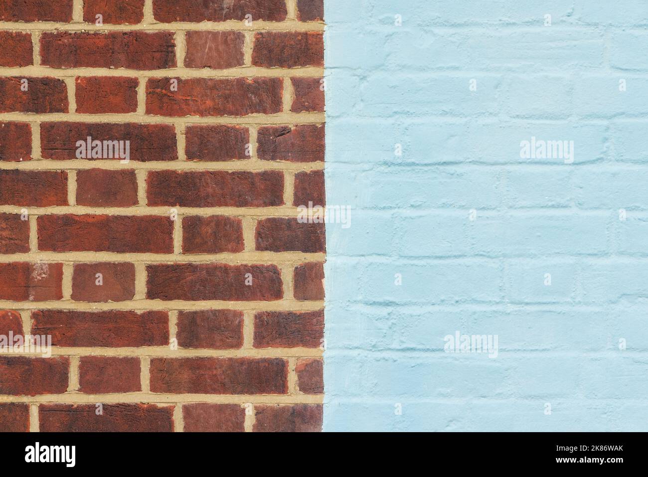 Half painted blue brick wall and bare brick. UK Stock Photo