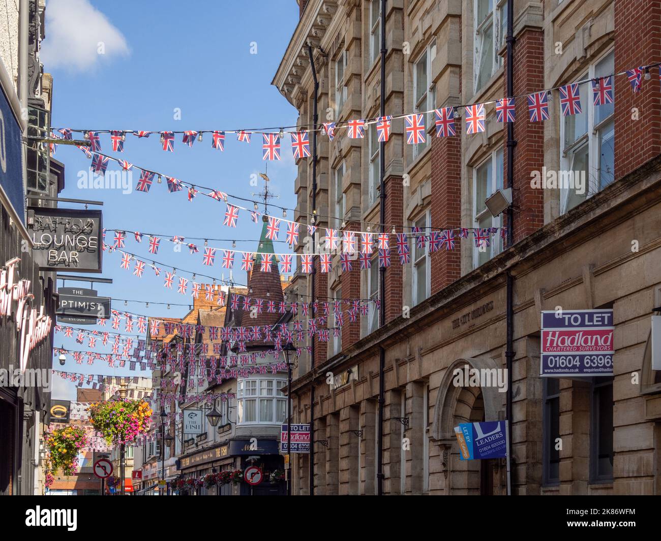 Roofline view of buildings in Fish Street, town centre, Northampton, UK; with Union Jack bunting flying between them. Stock Photo