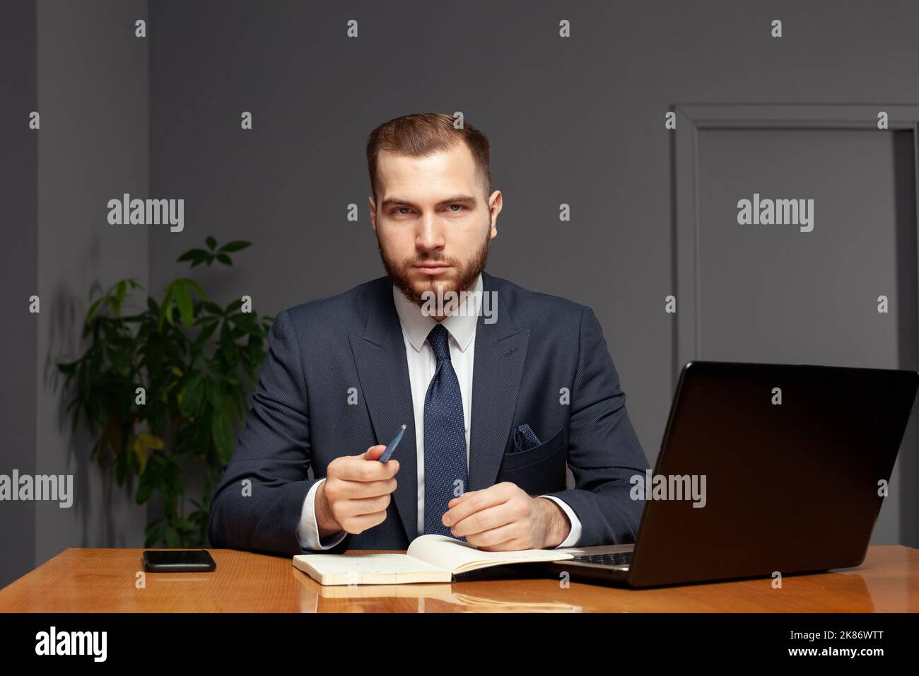 Confident successful businessman writes in his notebook. Multi-tasking concept Stock Photo