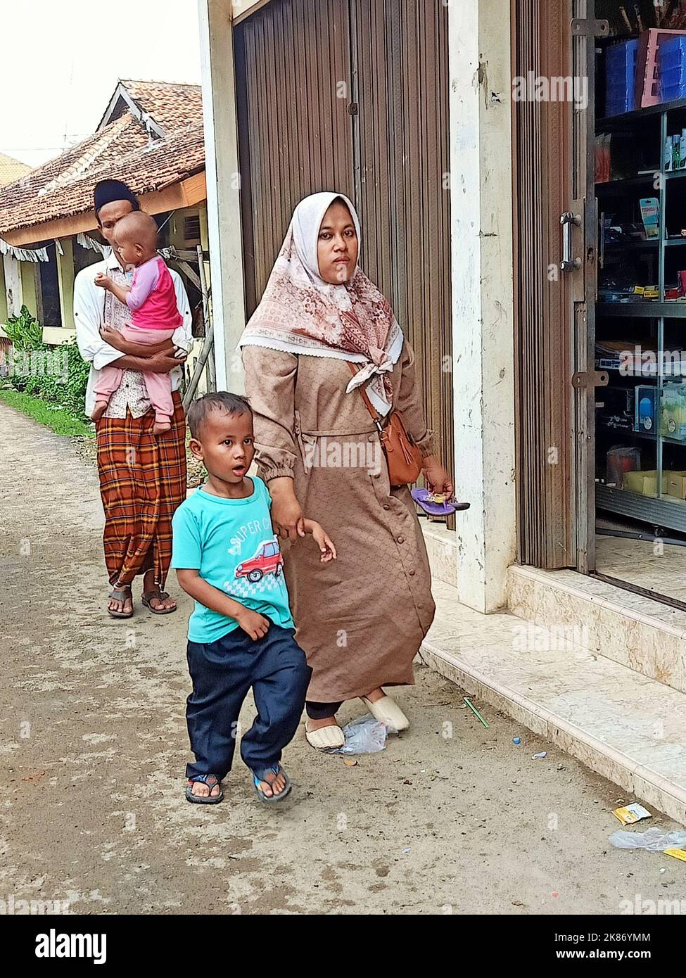 a moslem family is walking in a village alley Stock Photo