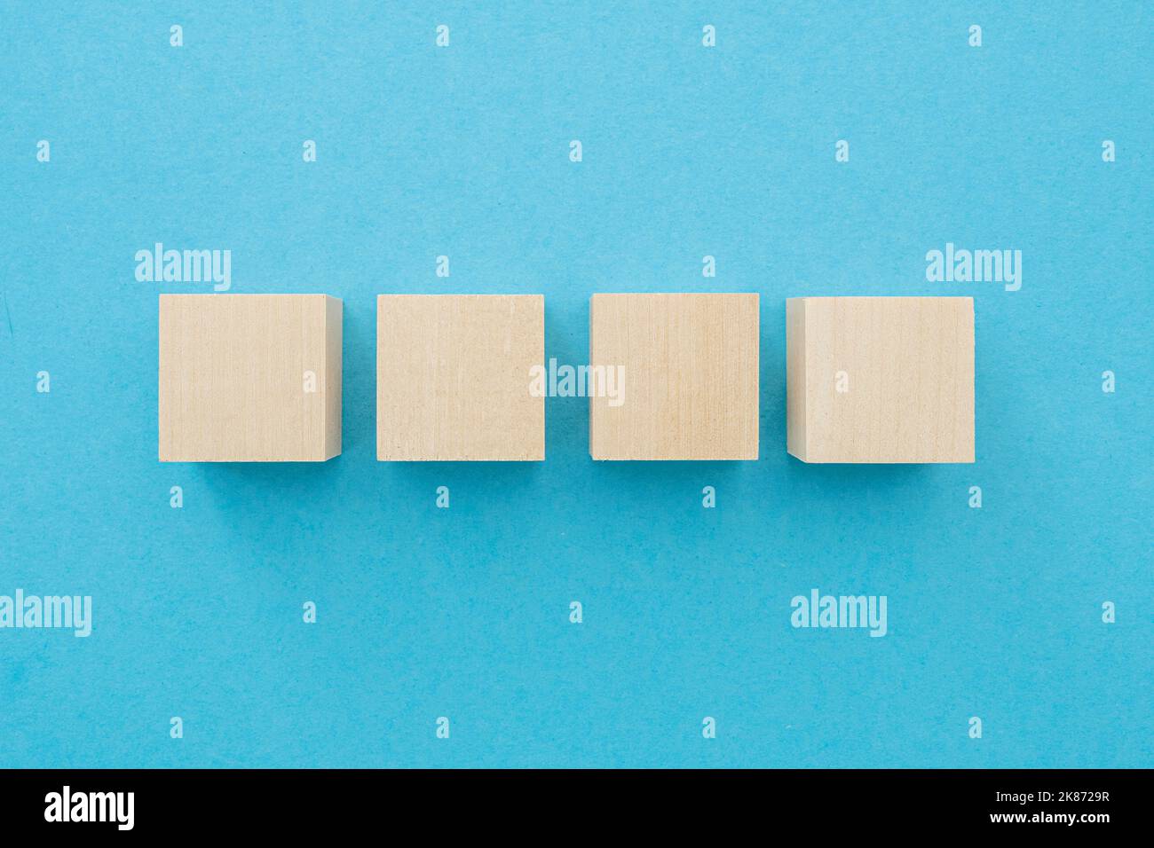 Four wooden cubes, square shape with blank surface on blue background, for business concept ideas Stock Photo