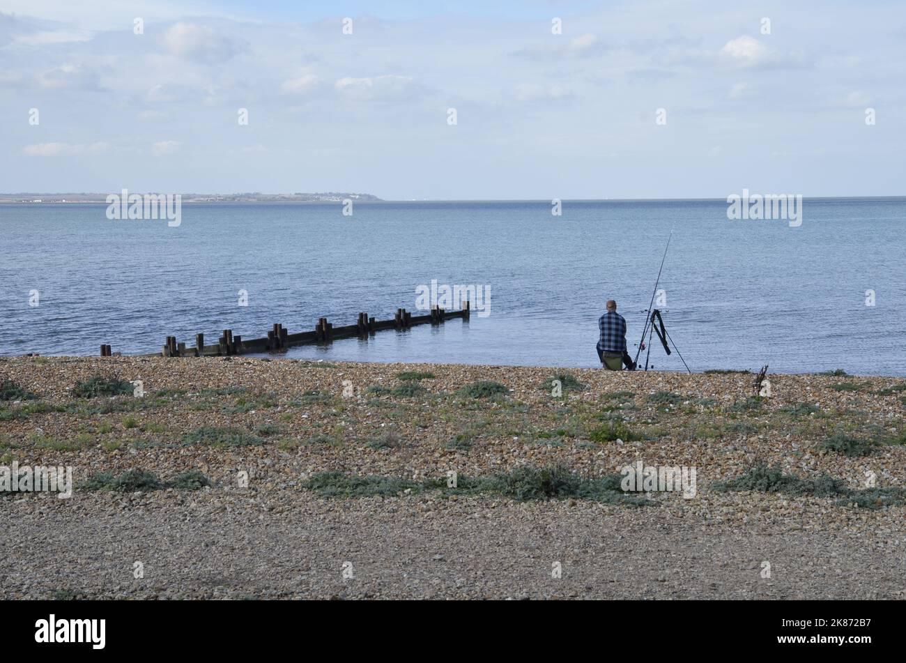 A man fishing on the beach at Whitstable in Kent Stock Photo