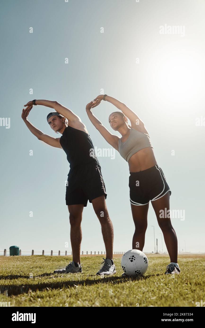 Soccer couple stretching at park, people workout on outdoor football