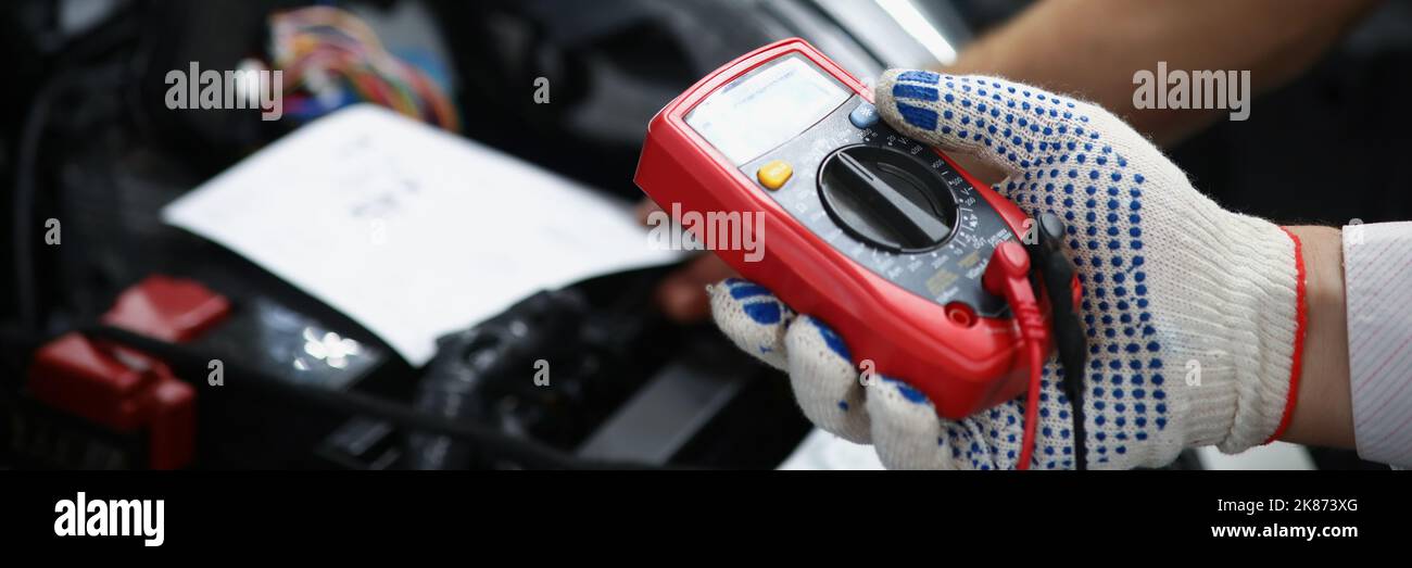 Mechanics hand hold multimeter equipment to measure voltage of automobile battery Stock Photo