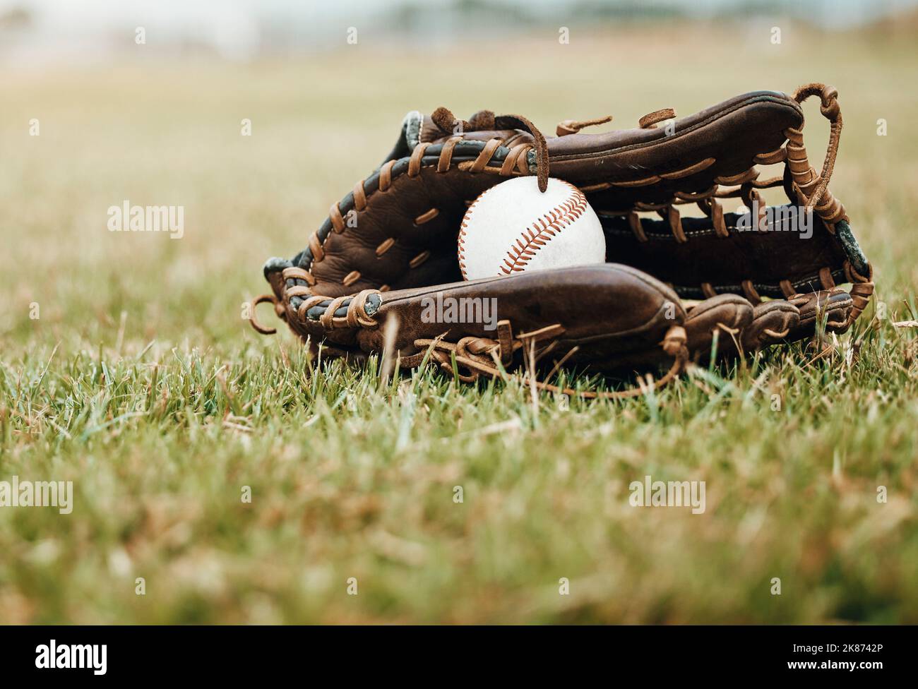 Baseball, sport and ball with glove on a grass pitch or field outdoor for a competitive game or match. Fitness, sports gear and skill with equipment Stock Photo