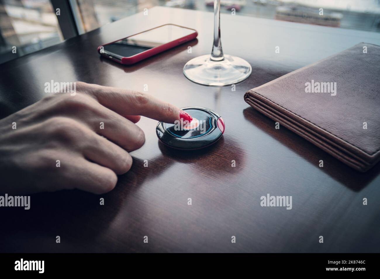 Female hand finger presses the button to call the waiter in the restaurant to pay for food for dinner. Pressing the buzzer. Good Tips. Stock Photo