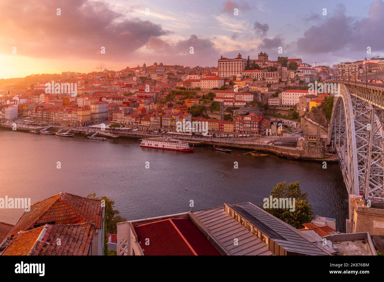 View of the Dom Luis I bridge over Douro River aligned with colourful buildings at sunset, looking towards the Ribeira district, UNESCO Stock Photo