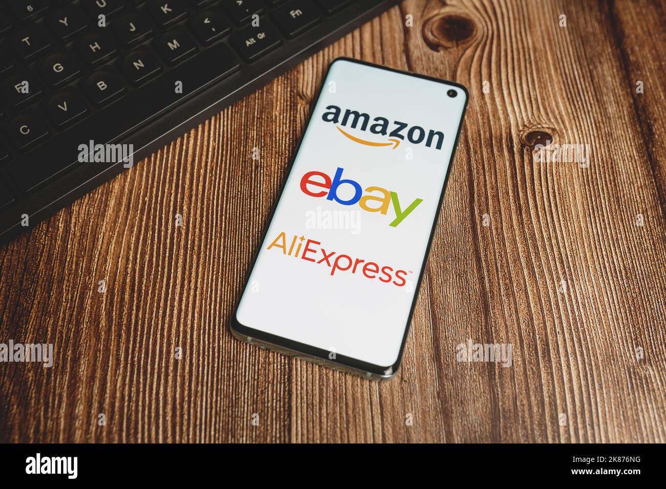 Amazon, Ebay, Aliexpress app logos on smartphone screen and black keyboard on wooden background. Dropshipping concept. Swansea, UK - March 19, 2021 Stock Photo