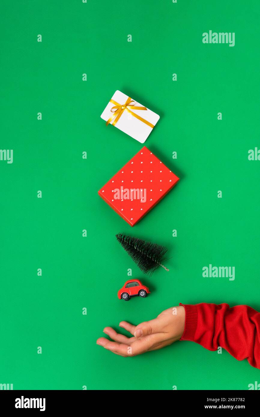 Minimal flat lay, bonus, gift card, gift box, christmas tree, car, levitate over hand. The concept of Christmas and New Year shopping, sales Bright gr Stock Photo