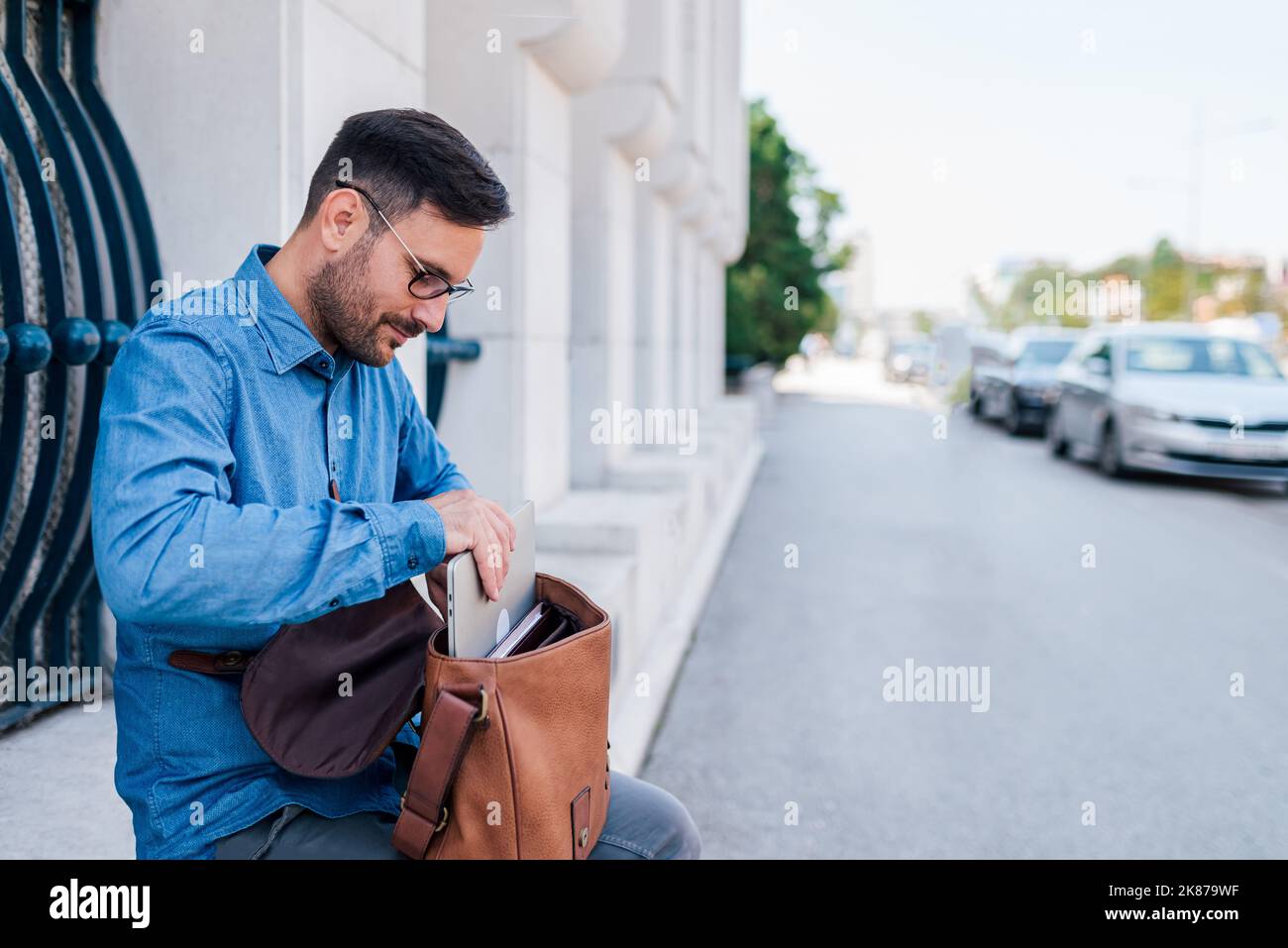 Relaxed adult man, preparing to work outside, getting his laptop ready for the job. Stock Photo
