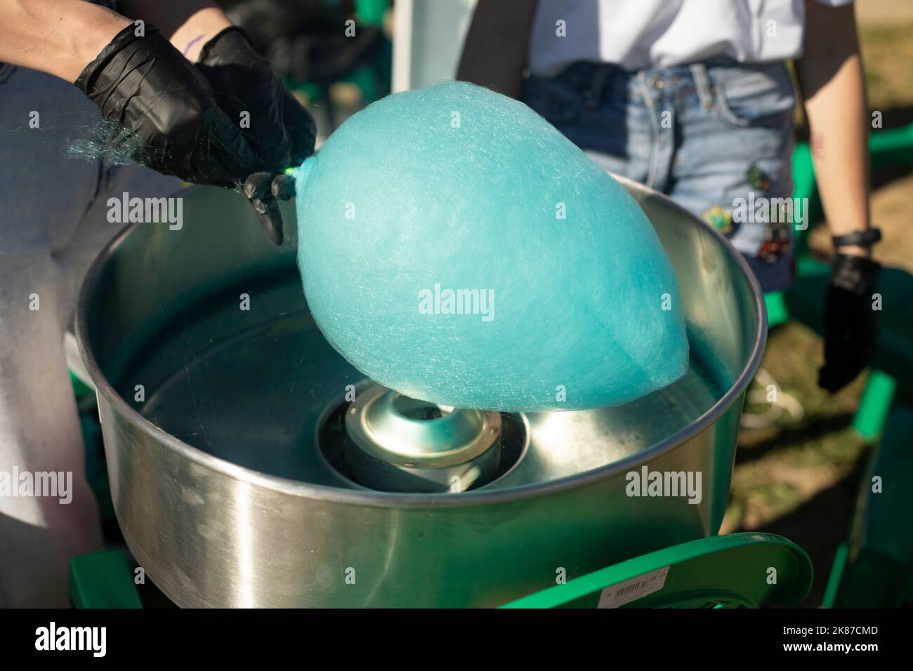 Cotton candy outside. Blue cotton candy on stick. Sugar product. Delicious food. Details of preparing treat. Stock Photo