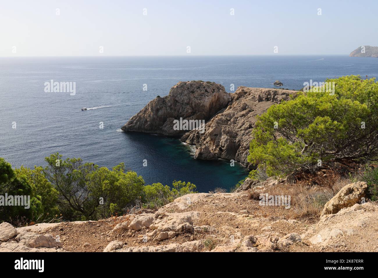 view into a beautiful small bay near Cala Ratjada, Mallorca with rocky outcrops and green vegetation in the foreground Stock Photo