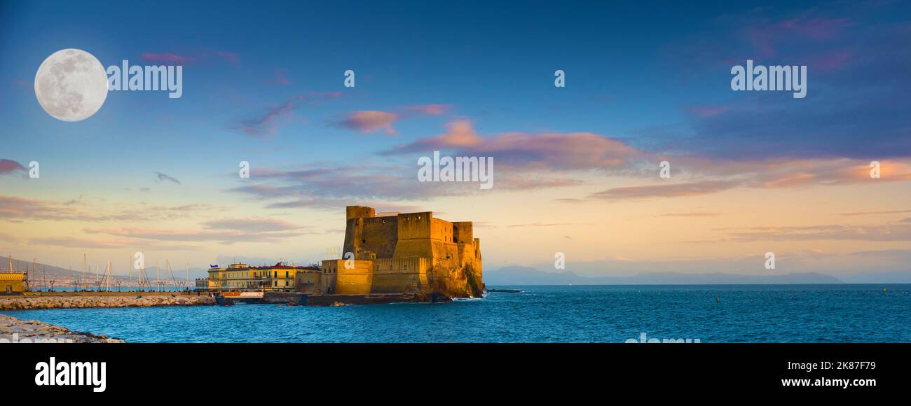 Naples, Italy. A big full Moon over Castel dell'Ovo with a beautiful  sunset sky. Banner Header. Stock Photo