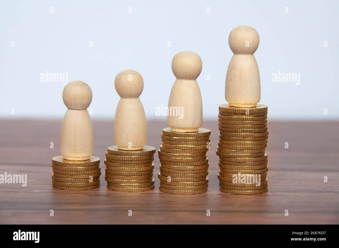 Wooden people figure on top of gold coins. Goal achievement, business growth and career progression. Stock Photo