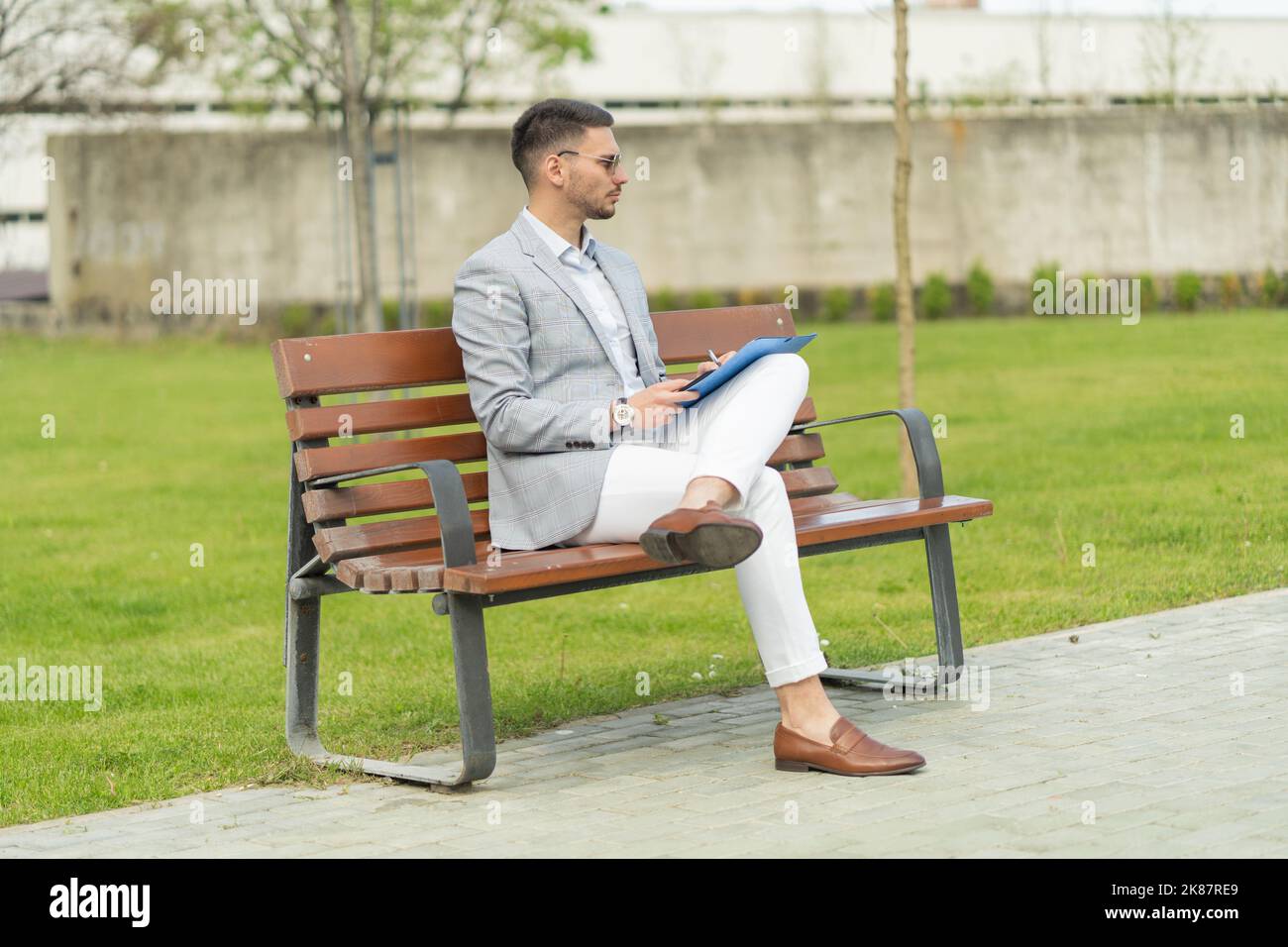 Urban businessman is sitting on the bench while working Stock Photo - Alamy