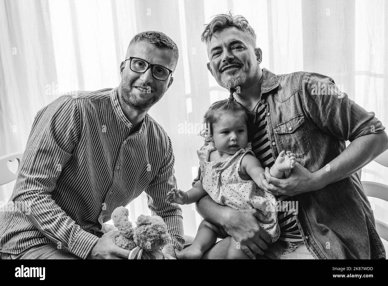 Portrait of happy LGBTQ family at home - Gay couple and their daughter - Diversity concept and LGBTQ family relationship - Black and white Stock Photo