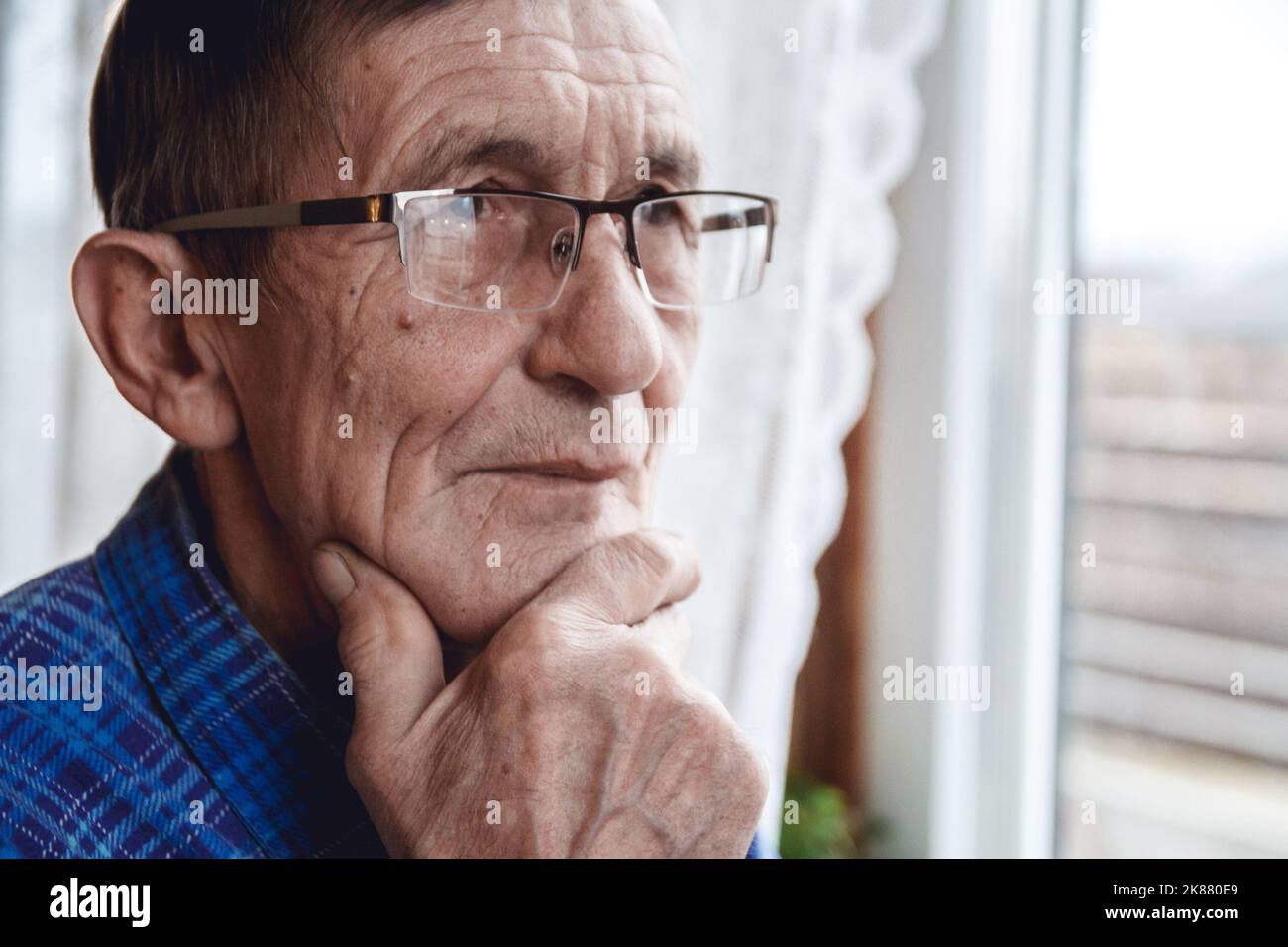 Senior standing at the window and thinking about something or fo Stock Photo