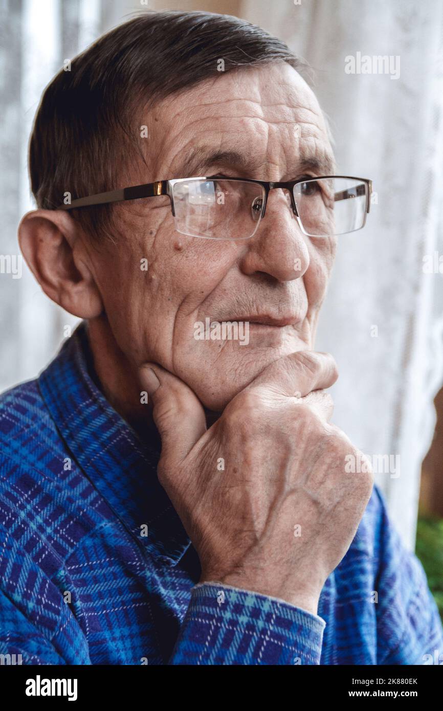 Senior standing at the window and thinking about something or fo Stock Photo