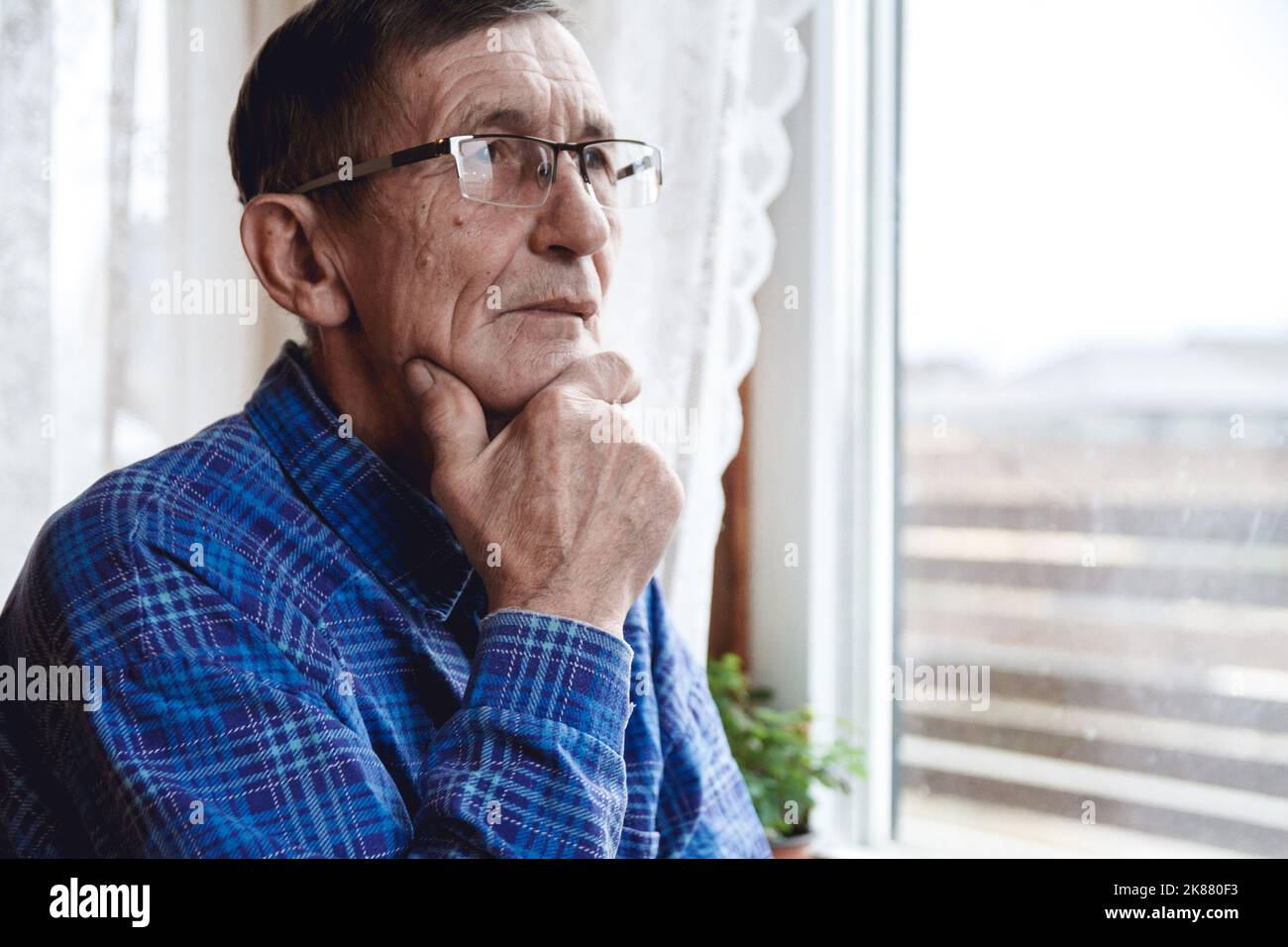 Senior standing at the window and thinking about something or fo Stock Photo
