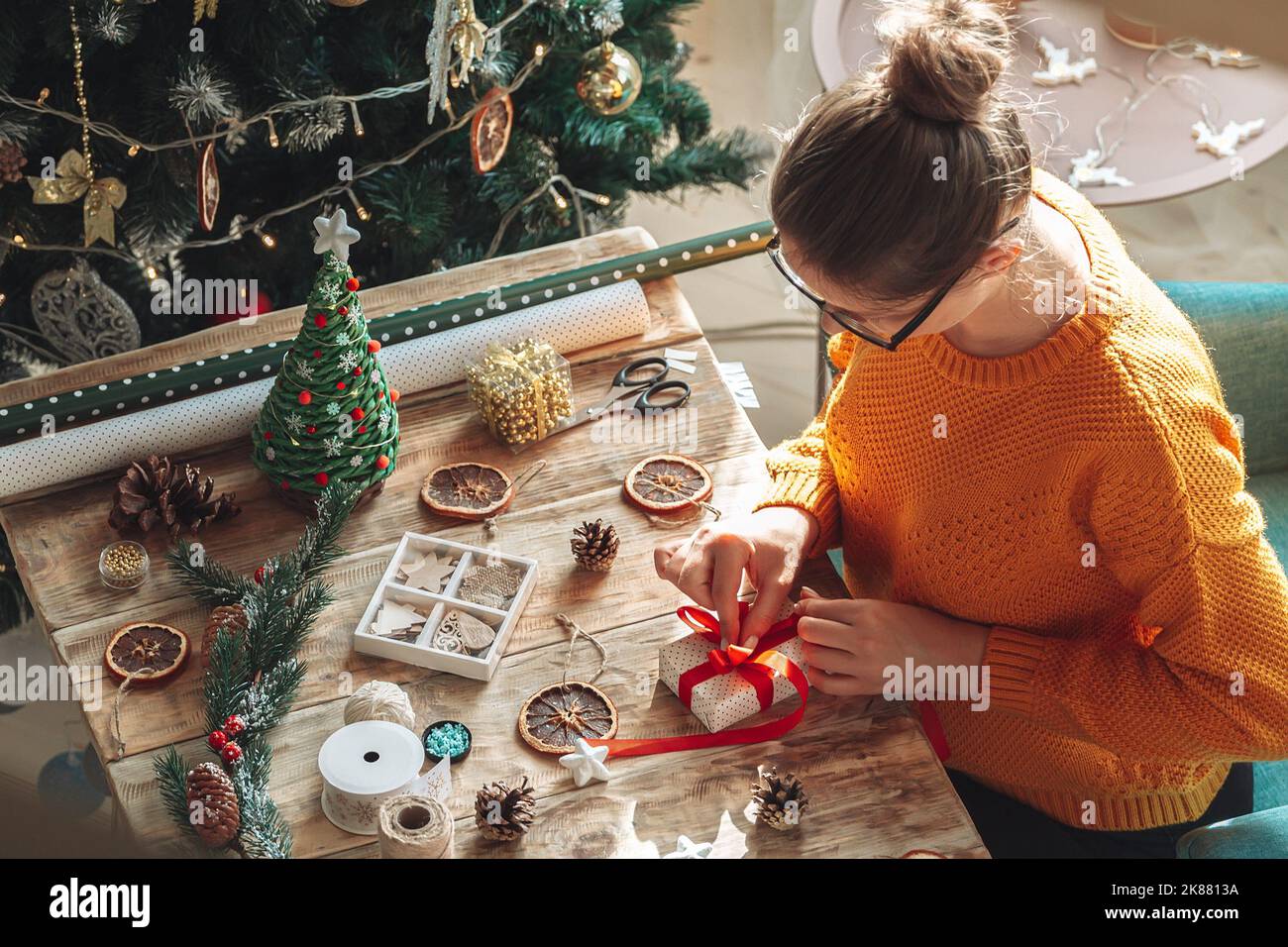 Young woman wrapping christmas present on table with new year de Stock Photo