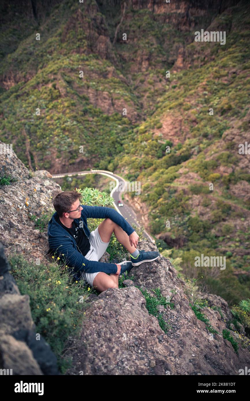 A Caucasian male hiker on top of a mountain during sunset in Masca, Tenerife, Spain Stock Photo
