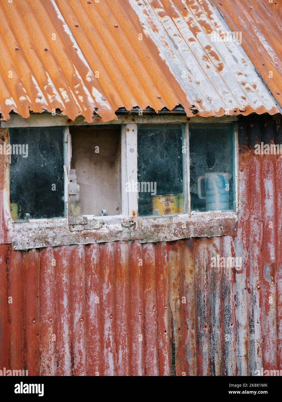 Dilapidated old painted tin shed with windows detail background. Stock Photo