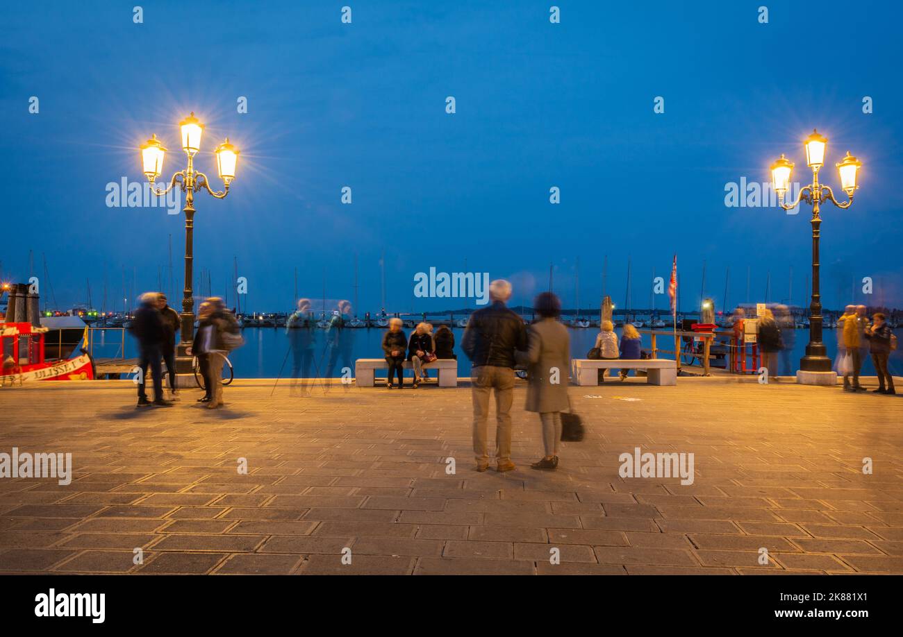 Tourists and locals relaxing and working on the Harbour waterfront -Chioggia Venetian Lagoon, Veneto regione, Italy, night photography - long exposure Stock Photo