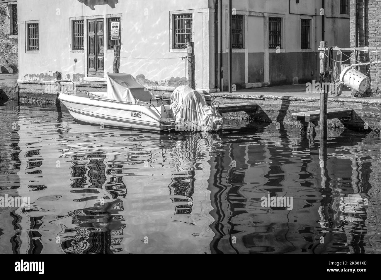 motorboat moored along the canal in Chioggia city, Venetian lagoon, Venice province, Veneto district, northern Italy- Europe - black and white image Stock Photo