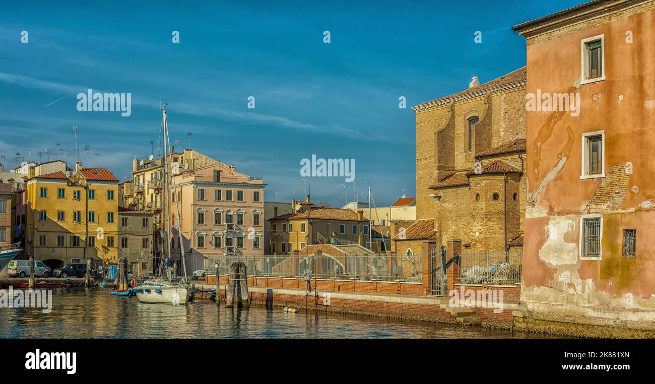 View of Chioggia town with narrow water canal with moored boats, buildings - Venetian lagoon, Venice province, northern Italy- Europe Stock Photo
