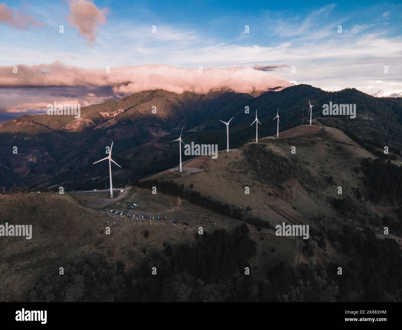 The wind turbines placed on top of mountains captured under a cloudy ...