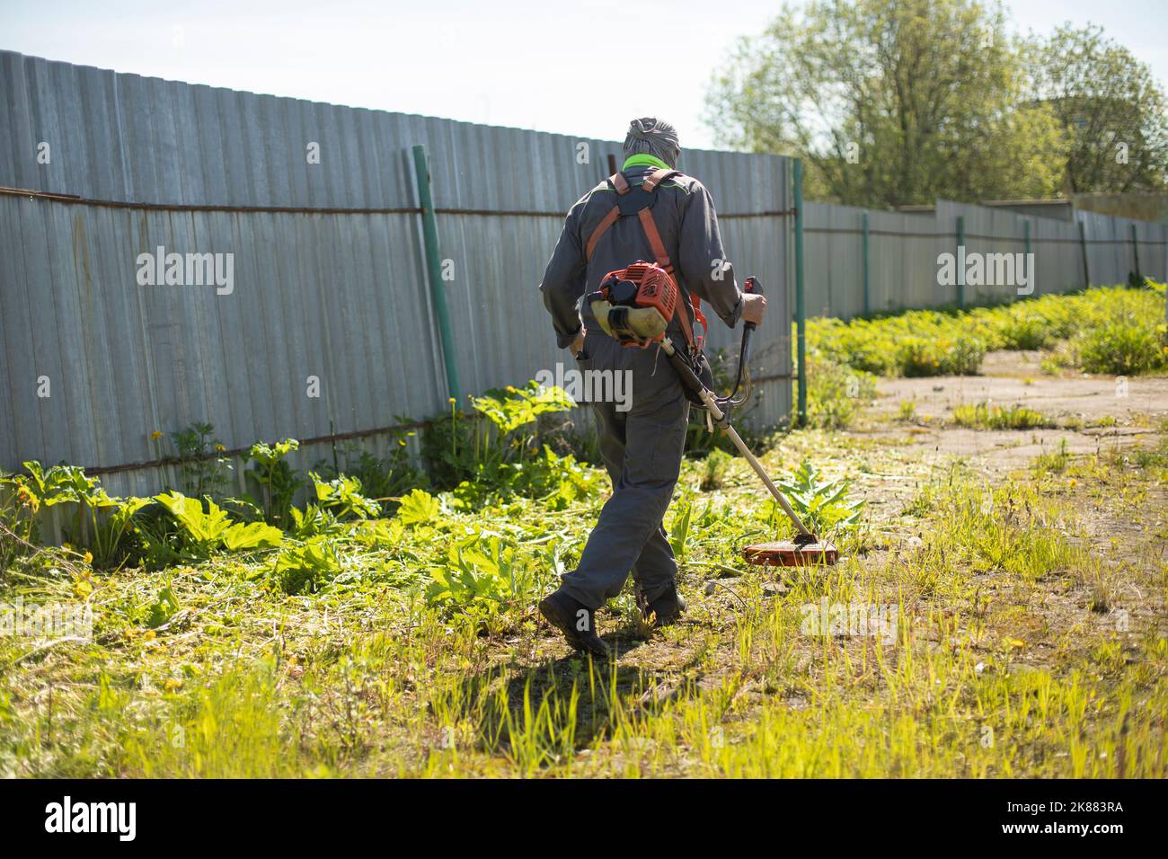 Mowing grass. Worker mows lawn. Gardener with gasolinepowered lawn