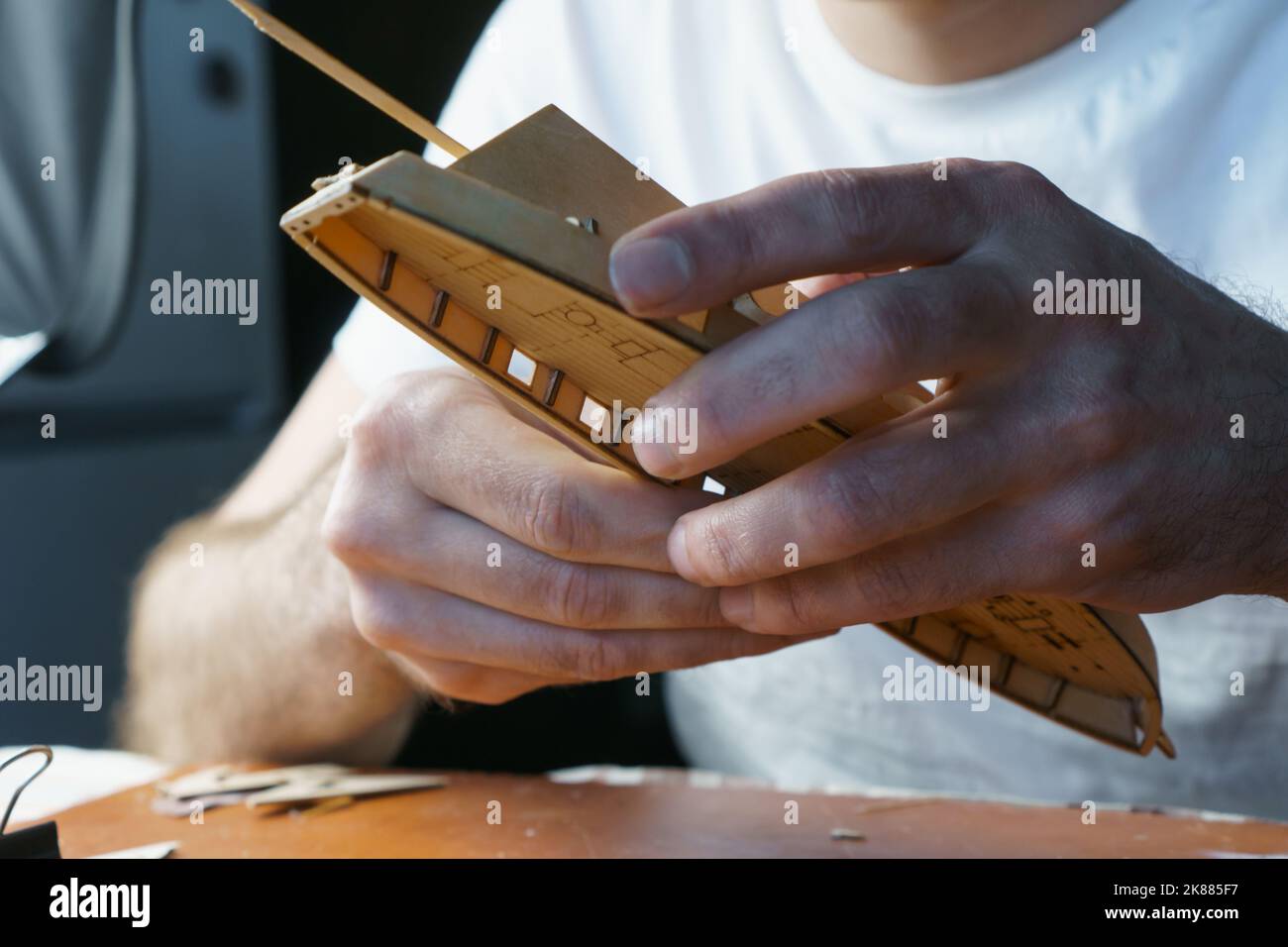 Hands of man gluing plywood details for ship model with glue, holding