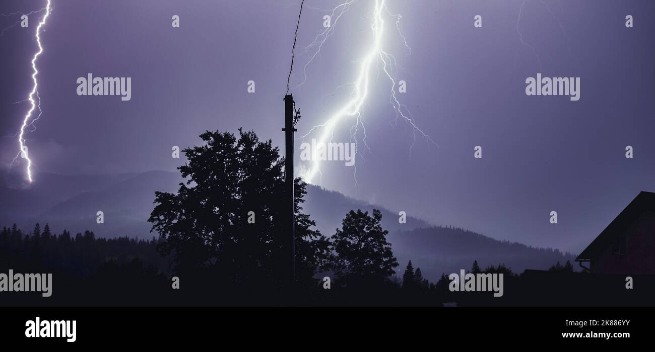 Two Lightning strike on the mountains in the night. Night mountain landscape. Flashes of light from thunder and lightning Stock Photo