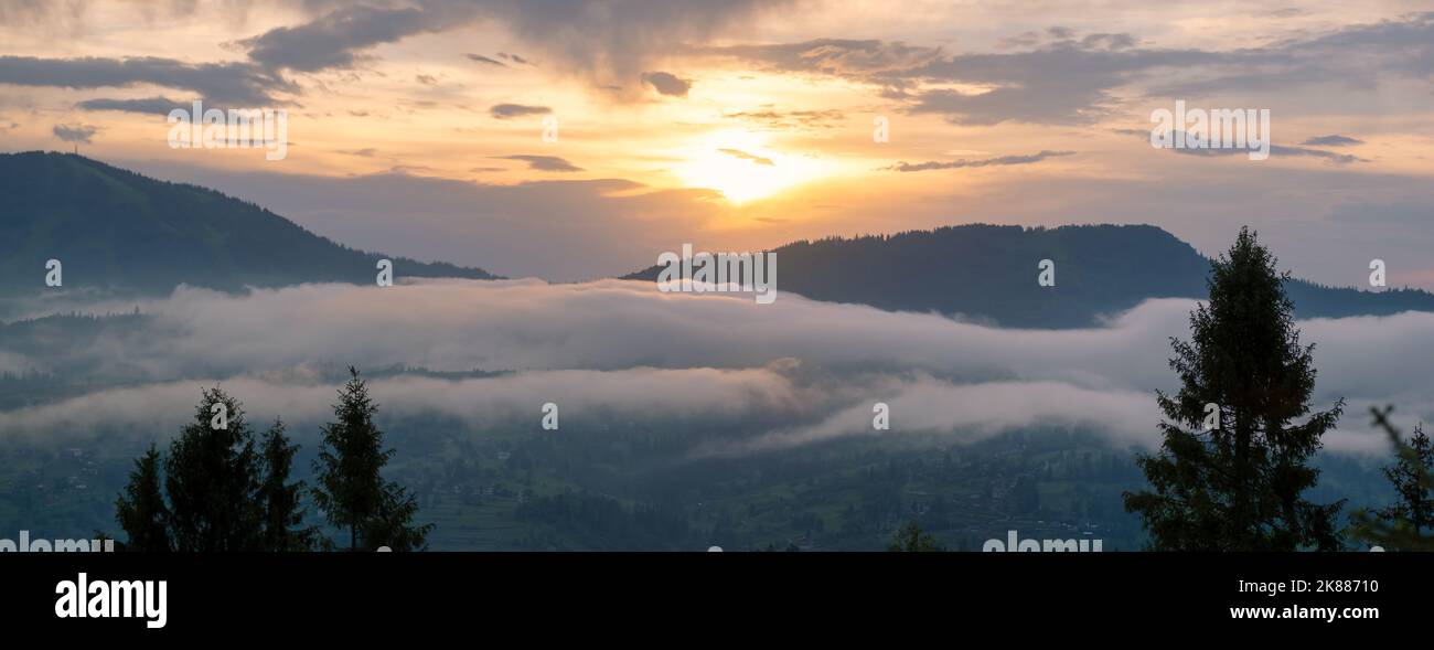 Beautiful landscape with fog on high mountains with peaks, mountain and yellow sunlight in sunrise. Amazing scene in mountains. Stock Photo