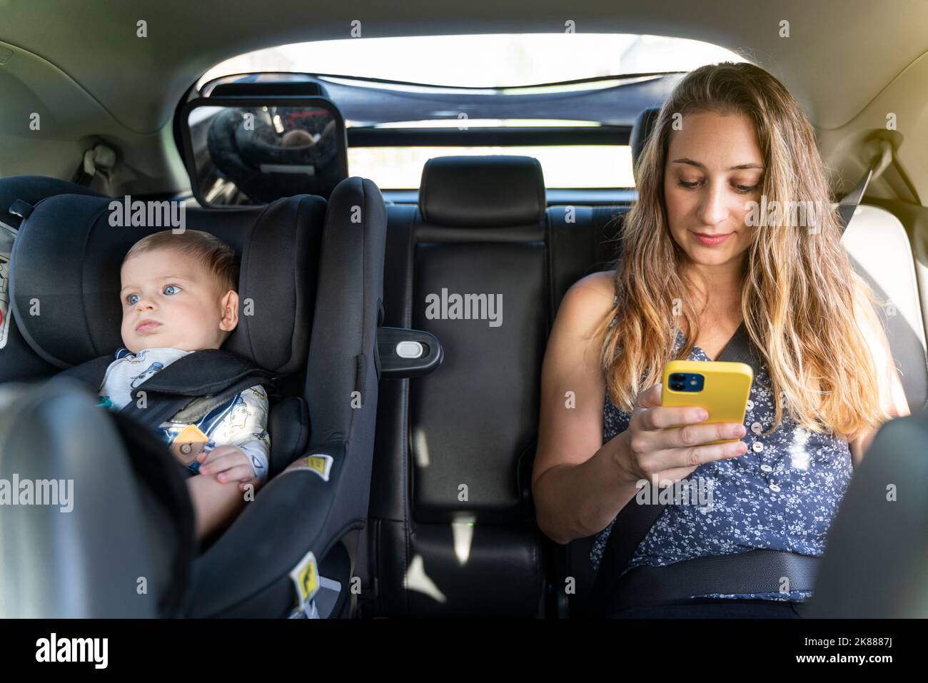 Mother with her son traveling by car in the back seats and using the phone Stock Photo