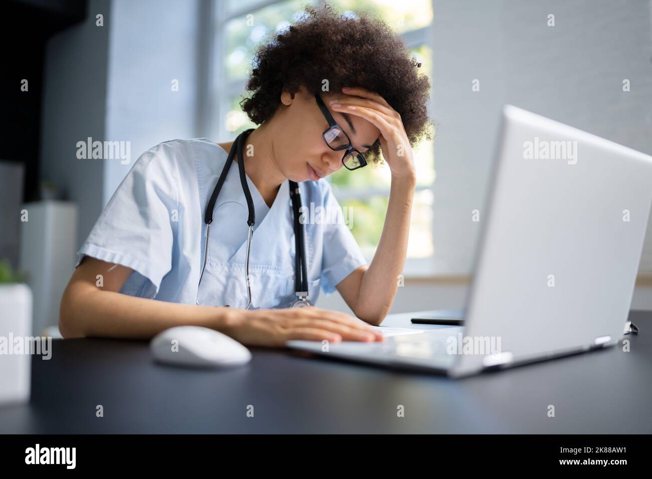 Frustrated Overworked Doctor In Hospital Looking At Computer Stock Photo