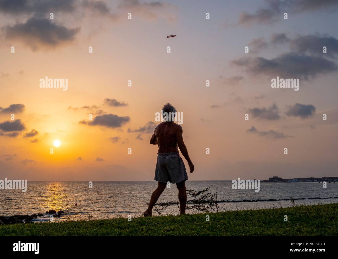 A man exercising on a beach throwing a frisbee, Paphos, Cyprus. Stock Photo