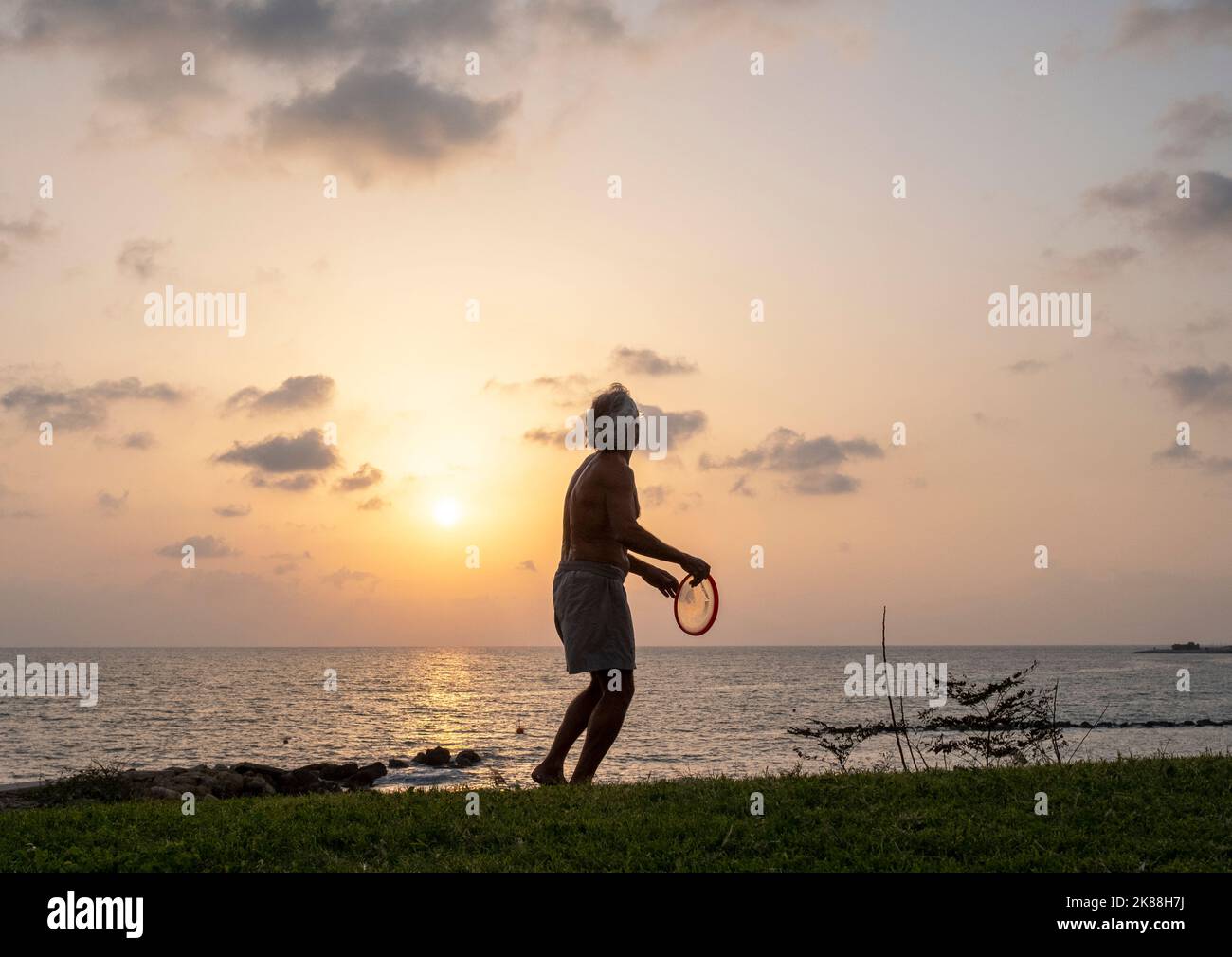 A man exercising on a beach throwing a frisbee, Paphos, Cyprus. Stock Photo