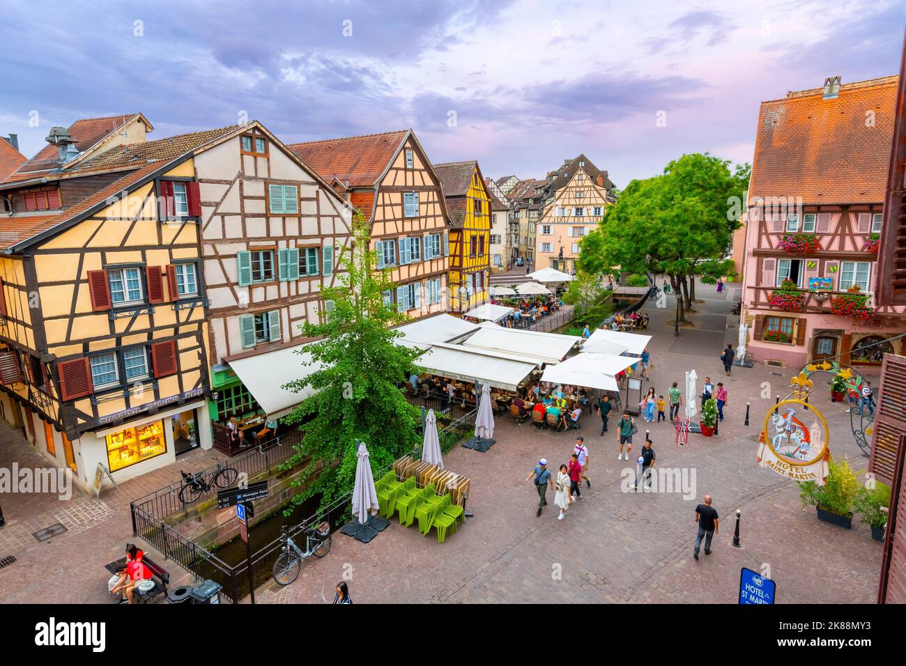 A picturesque street of shops and sidewalk cafes in the medieval old town of Colmar, France, one