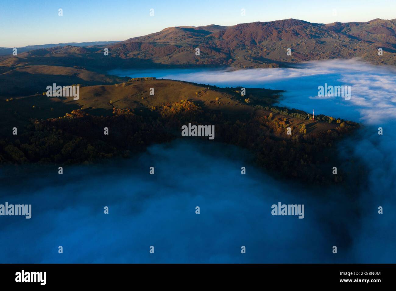 Aerial drone view of mist and clouds in the valley in sunrise. Flying Above the clouds Stock Photo