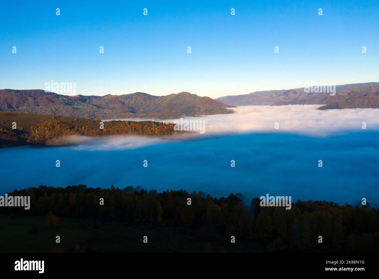 Flying above the clouds in dawn. Misty morning in the valley, aerial drone view Stock Photo