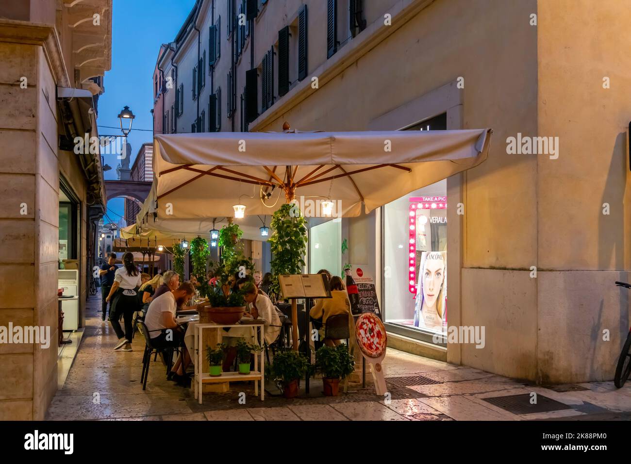 A small sidewalk outdoor cafe in the medieval old town of Verona, Italy, at night. Stock Photo