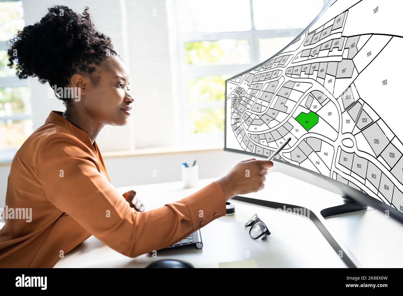 African American Using Cadastral Map On Desktop Computer Stock Photo